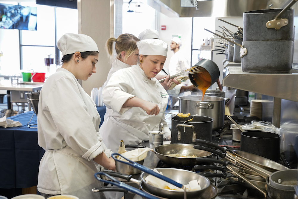 Two students cooking in a culinary arts kitchen